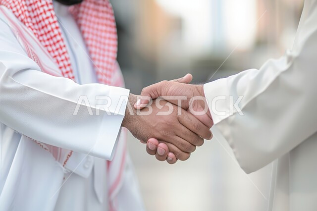 صداقات وتعارف وبناء علاقات اجتماعية، عقد صفقات عمل جديدة ناجحة بين رجال الأعمال، الشراكة في الأعمال والمشاريع، صورة مقربة ليدين رجلان سعوديان يقومان بمصافحة بعضهما، توسيع مجالات العمل