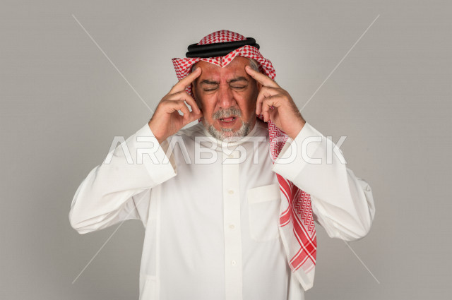 بورتريه لرجل كبير بالسن سعودي خليجي  مريض بإيماءات الوجه و اليدين التي تدل على الألم والمعاناه،  تعابير وجه ، خلفية بيضاء