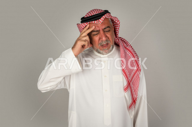 بورتريه لرجل كبير بالسن سعودي خليجي  مريض بإيماءات الوجه و اليدين التي تدل على الألم والمعاناه،  تعابير وجه ، خلفية بيضاء