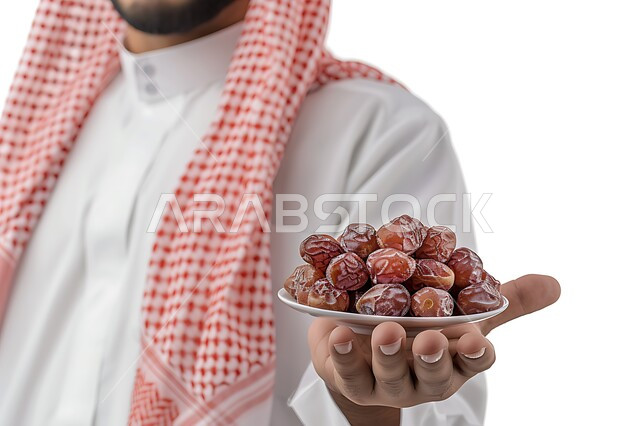 أنواع التمور الفاخرة في المملكة العربية السعودية، بورتريه مقرب لرجل عربي خليجي سعودي يرتدي الزي التقليدي والشماغ يحمل بيده مجموعة من حبات التمر الطازجة، ثمار ومحاصيل زراعية محلية وطنية، وجبة ذات قيمة غذائية عالية، خلفية رمادية