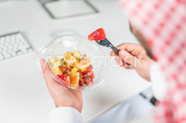 رجل سعودي يتناول سلطة فواكه مفيدة لذيذة , حمية غذائية صحية , تناول الفواكه الطازجة مفيد للصحة . 