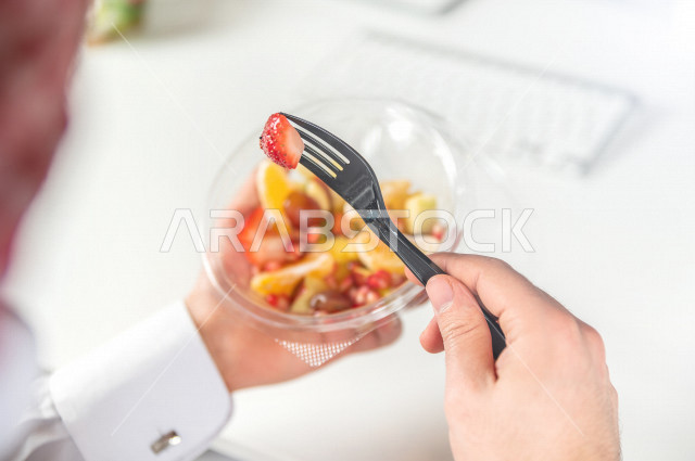 رجل سعودي يتناول سلطة فواكه مفيدة لذيذة , حمية غذائية صحية , تناول الفواكه الطازجة مفيد للصحة . 
