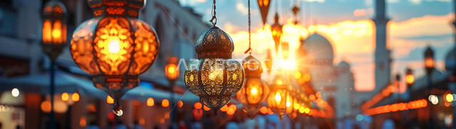 Greeting cards for Islamic religious occasions and holidays, distinctive Ramadan decorations, decorations and lights, a panoramic picture of the golden hanging lanterns illuminating the center of the city at sunset, traditional antiques to celebrate the coming of the month of goodness, the background of mosques and mosques