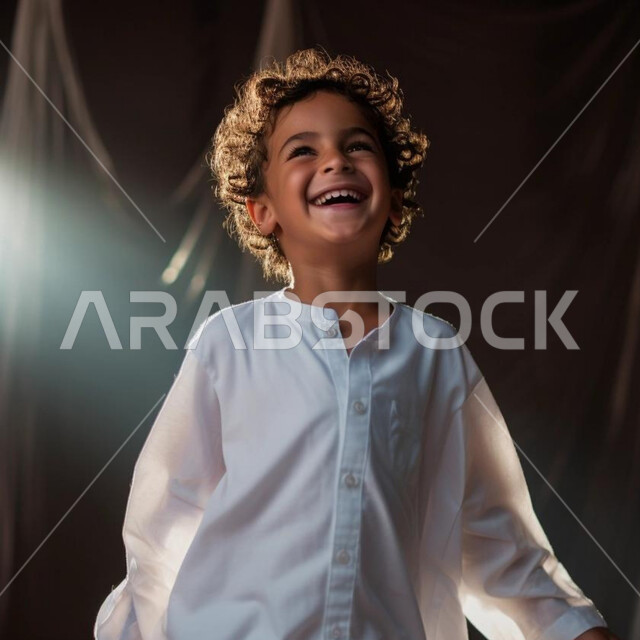 التحضير والتجهيز للاحتفال بالأعياد والمناسبات الإسلامية السعيدة ، فرحة وبهجة الأطفال بالعيد السعيد، ايماءات الحماس والسعادة والضحك الشديد، ولد عربي خليجي سعودي يرتدي الثوب التقليدي