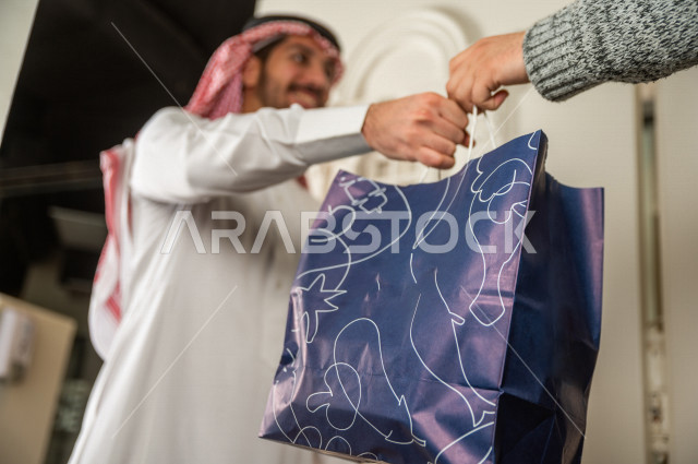A Saudi man receives his order in front of the door, wholesome, useful meals, delivery of orders.