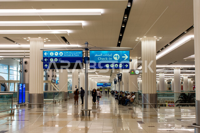 Electronic guidance screens, passengers standing in the passenger reception halls, the distinctive interiors and engineering art of Dubai International Airport, the concept of tourism and travel in the United Arab Emirates, the most important air hub in the Middle East