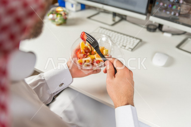 رجل سعودي يتناول سلطة فواكه مفيدة لذيذة , حمية غذائية صحية , تناول الفواكه الطازجة مفيد للصحة . 