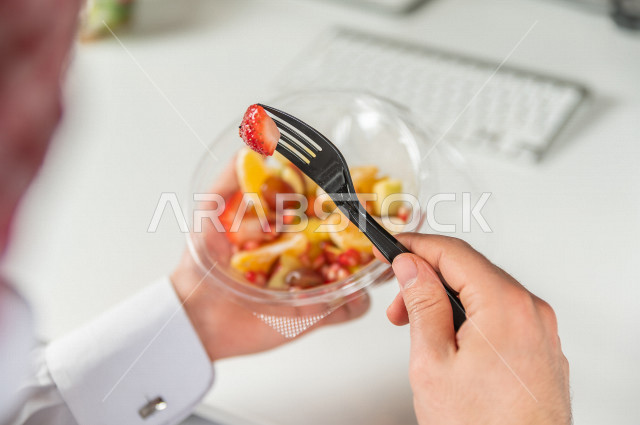 رجل سعودي يتناول سلطة فواكه مفيدة لذيذة , حمية غذائية صحية , تناول الفواكه الطازجة مفيد للصحة . 