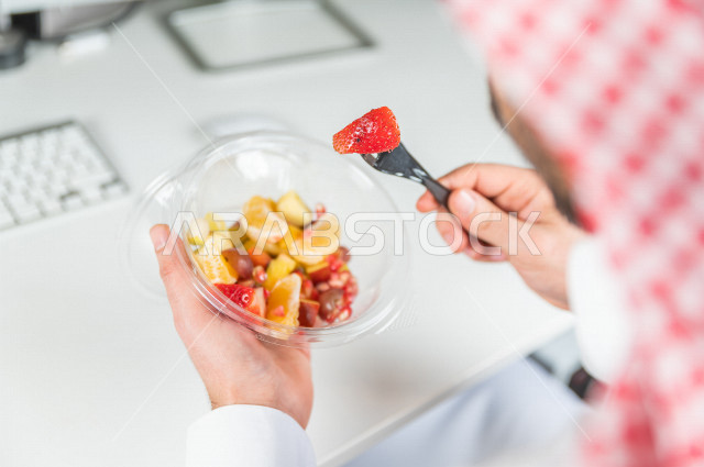 رجل سعودي يتناول سلطة فواكه مفيدة لذيذة , حمية غذائية صحية , تناول الفواكه الطازجة مفيد للصحة . 