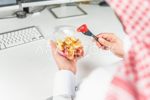 A Saudi man eats delicious fruit salad, a healthy diet, eating fresh fruits is good for health.