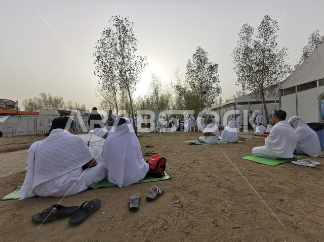 A group of pilgrims and Umrah pilgrims praying and approaching God next to the pilgrims’ tents in Mina, Mecca, in the Kingdom of Saudi Arabia, sacred religious places, performing Hajj and Umrah rituals, Islamic landmarks in Saudi Arabia.