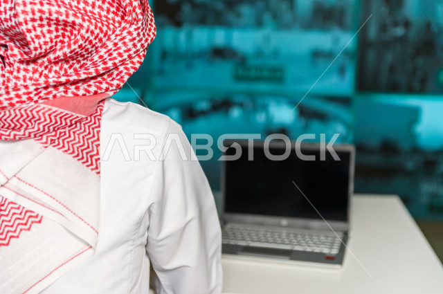 رجل سعودي خليجي يدير القسم الامني  ، يقوم بتتبع كاميرات المراقبة  ، يرتدي الزي السعودي التقليدي ، الحفاظ على الامن و الطمأنينة ، حراسة و امان 