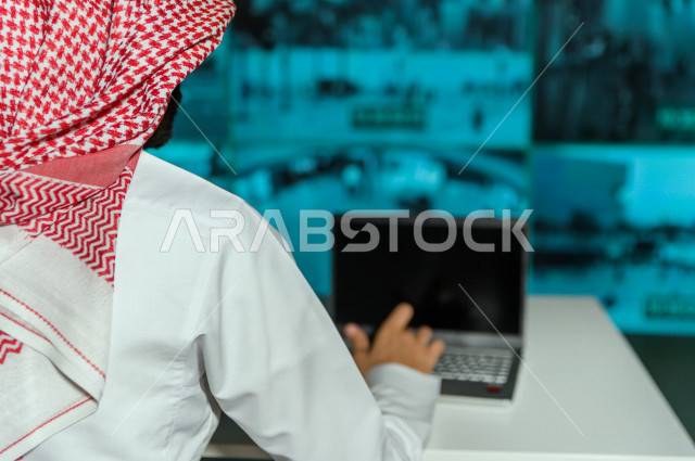 رجل سعودي خليجي يدير القسم الامني  ، يقوم بتتبع كاميرات المراقبة  ، يرتدي الزي السعودي التقليدي ، الحفاظ على الامن و الطمأنينة ، حراسة و امان 