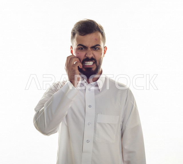 Portrait of a Saudi Gulf man with several problems in the face area, exposure to burns, facial blisters spread on the skin, gestures and facial expressions and hands indicating pain and sadness, health problems and physical injuries, white background