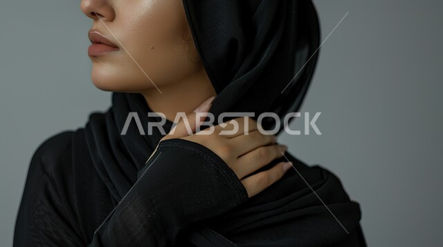 طلب المساعده والحاجه للعلاج، التهاب العضلات والمفاصل، المعاناة من الآلام والأوجاع العصبية والعضلية، بورتريه مقرب لإمرأة عربيه سعوديه خليجيه ترتدي العباءة والحجاب تضع يدها على كتفها بإيماءات الألم والتعب والأرهاق, خلفية رمادية