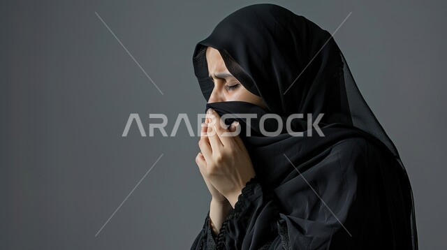 الشعور بالتعب والمرض، الإصابة بفايروس كورونا كوفيد19، بورتريه مقرب من الجانب لامرأه عربيه خليجيه سعوديه منقبة ترتدي عباءة سوداء، إيماءات وجه ويدين تدل على العطاس، خلفية رمادية