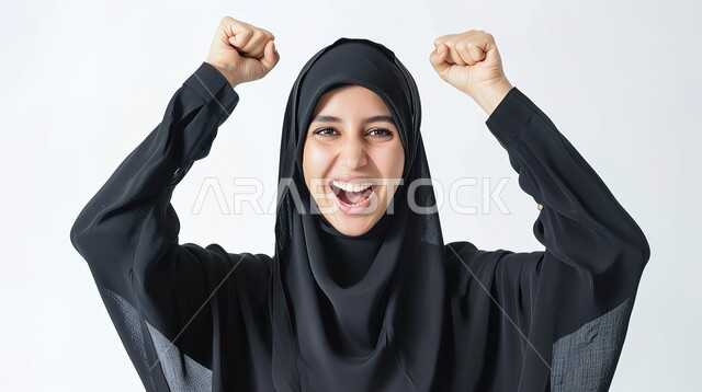 تعابير السرور والسعادة، مفهوم الفرح بالنصر والفوز، النجاح وتحقيق الأهداف، بورتريه مقرب لامرأة عربية خليجية سعودية محجبة مبتسمة ترتدي عباءة سوداء ترفع يديها بإيماءات الحماس، خلفية بيضاء