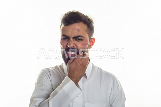 بورتريه لرجل سعودي خليجي مصاب بعدة مشاكل في منطقة الوجه، التعرض للحروق ،  بثور وجه منتشرة على البشرة ، ايماءات و تعبيرات وجه و يدين تدل على الآلم و الحزن ، مشاكل صحية و اصابات جسدية ، خلفية بيضاء