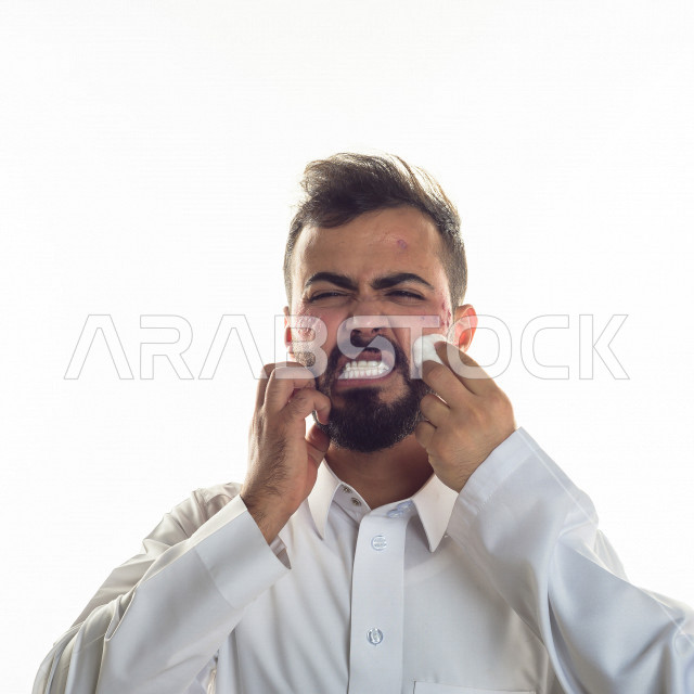 بورتريه لرجل سعودي خليجي مصاب بعدة مشاكل في منطقة الوجه، التعرض للحروق ،  بثور وجه منتشرة على البشرة ، ايماءات و تعبيرات وجه و يدين تدل على الآلم و الحزن ، مشاكل صحية و اصابات جسدية ، خلفية بيضاء