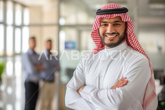 مهن ووظائف ادارية سعودية، توضيح مهام العمل واستراتيجيات الشركة، مفهوم الأناقة والإهتمام بالمظهر الخارجي، رجل أعمال عربي خليجي سعودي مبتسم يرتدي الثوب التقليدي والشماغ ينظر الى الكاميرا يقف باستقامة وايدي متقاطعة