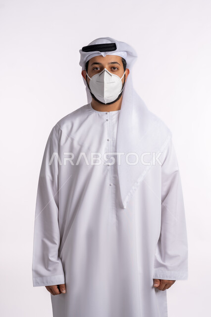 تجنب الملامسه السطحيه والحفاظ على المسافات، إتباع الإجراءات الوقائيه ضد الفايروسات، بورتريه لرجل عربي خليجي اماراتي يرتدي الكندوره والغتره البيضاء يضع القناع الطبي الوقائي للوقايه من فايروس كورونا، خلفيه بيضاء
