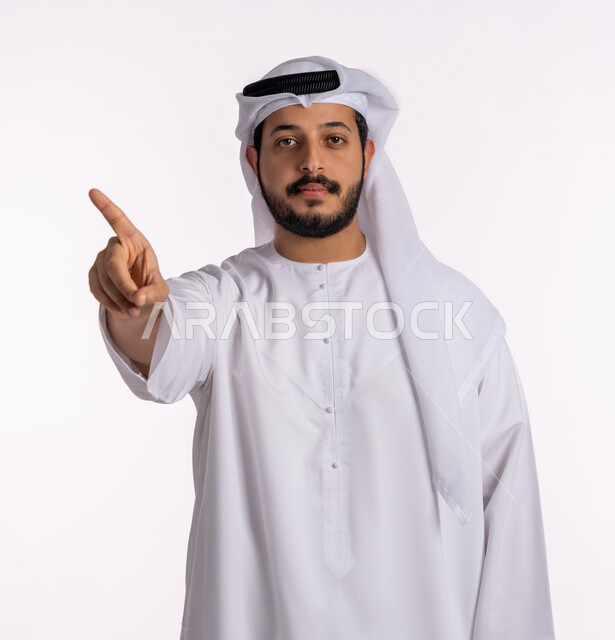 Locating a specific thing, gestures and hand movements indicating this place (here), a close-up portrait of an Arab Gulf Emirati man wearing a kandura and a white ghutra, pointing with his finger upwards, the concept of elegance and concern for external appearance, a white background.