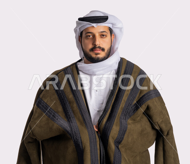 الاهتمام بالمظهر الخارجي، مفهوم الرجولة والاناقة، الوقوف باستقامة والنظر إلى الكاميرا بايماءات الثقة بالنفس، الملابس المناسبة لفصل الشتاء، الأجواء الشتوية الباردة، بورتريه مقرب لرجل عربي خليجي إماراتي يرتدي الفروة الغترة البيضاء، خلفية بيضاء