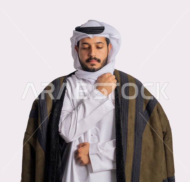 تعابير التعب والإرهاق، الشعور بالصقيع والقشعريرة والتجمد، إيماءات وجه ويدين تدل على البرد الشديد، الأجواء الشتوية الباردة، بورتريه مقرب لرجل عربي خليجي اماراتي يرتدي الفروة والغترة البيضاء، ارتداء الملابس المناسبة لفصل الشتاء، خلفية بيضاء