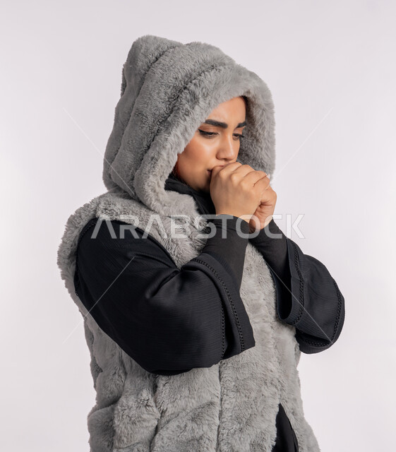 الانفلونزا والتهاب الرئة، الشعور بالمرض والكحة، الاجواء الشتوية الباردة، بورتريه مقرب من الجانب لامرأة عربية خليجيه اماراتية ترتدي معطف شتوي تعاني من السعال، شابة سعودية مصابة بفايروس كورونا كوفيد19، خلفية رمادية