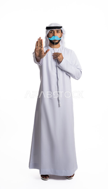 الإيماءات العالمية للتحذير والتنبيه، بورتريه لرجل عربي خليجي إماراتي يرتدي يرتدي الغترة والكندورة ويرفع يده لمنع الاقتراب الشديد منه ويمسك بقصاصة ورقية بشكل شارب، مناسبات عالمية سنوية، مفهوم الاهتمام بالرجل، الطول الكامل للجسم، خلفية بيضاء