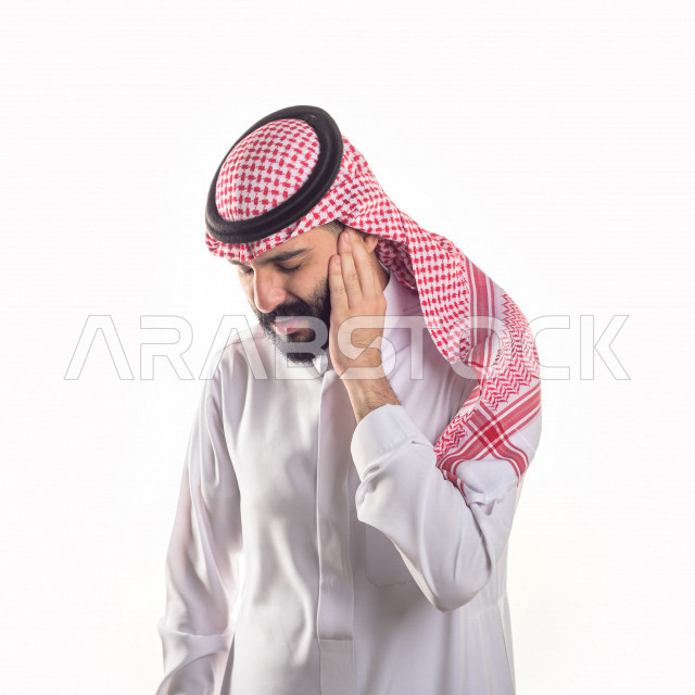 بورتريه لرجل سعودي خليجي يعاني من التهابات الاذن ،بإيماءات الوجه و اليدين التي تدل على الألم والمعاناه ، خلفية بيضاء