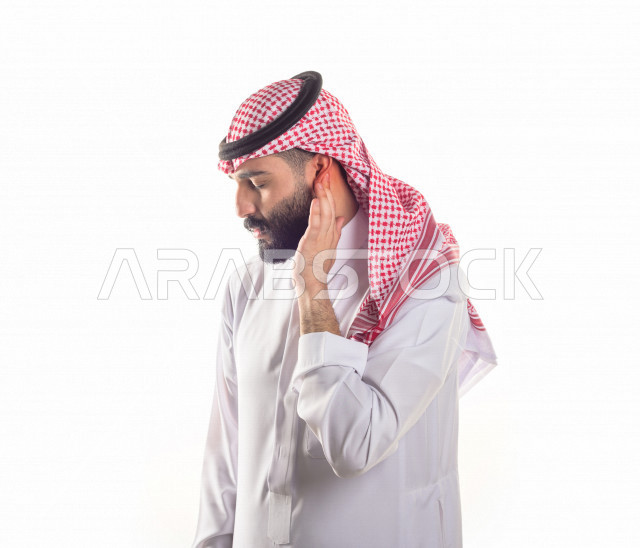 بورتريه لرجل سعودي خليجي يعاني من التهابات الاذن ،بإيماءات الوجه و اليدين التي تدل على الألم والمعاناه ، خلفية بيضاء