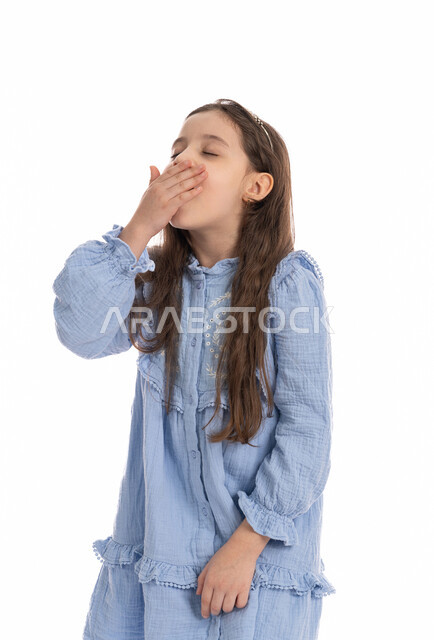 A feeling of laziness, lethargy and exhaustion, a close-up portrait of an Arab Emirati Gulf girl putting her hand on her mouth with gestures of yawning and sleepiness, a Saudi girl wearing a dress and feeling tired and in need of sleep and rest, white background