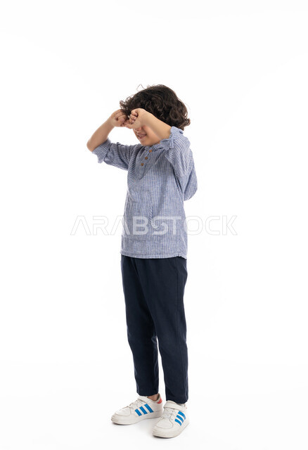 الشعور بألم في العيون، الندم على شيء ما، الحزن والإحباط والرغبه بالبكاء, بورتريه لولد عربي اماراتي خليجي يرتدي الزي الكاجوال يضع يديه على عينيه بايماءات تدل على الشعور بالخيبه, الخساره والفشل، صورة الجسم بالكامل، خلفية بيضاء