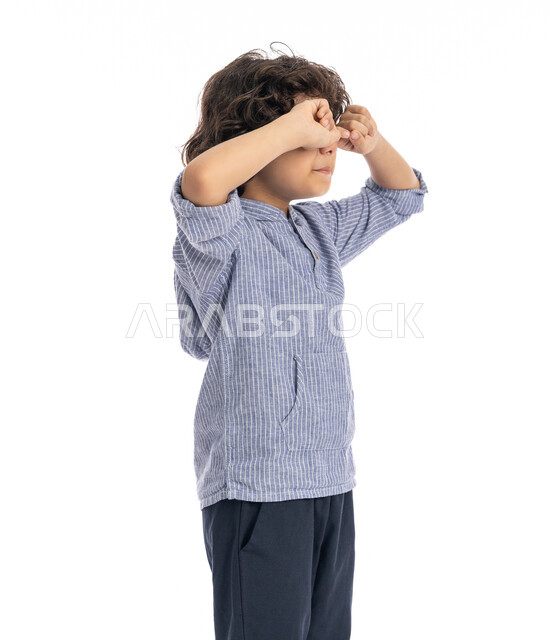 الحزن والإحباط والرغبه بالبكاء, بورتريه مقرب لولد عربي اماراتي خليجي يرتدي الزي الكاجوال يضع يديه على عينيه بايماءات تدل على الشعور بالخيبه, الشعور بألم في العيون، الندم على شيء ما, الخساره والفشل، خلفية بيضاء