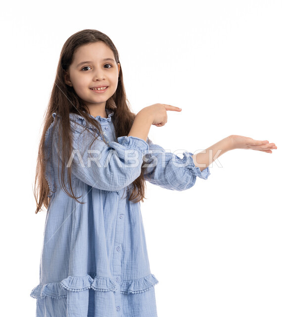 النقر بالأصبع على الشاشه, بنت سعودية ترتدي الفستان و تستخدم حاسة اللمس لتحريك العناصر الهولوجراميه, بورتريه مقرب لفتاة عربية اماراتية خليجية تشير الى شيء ما تحمله في يدها, الشعور بالإعجاب والرضا, خلفية بيضاء