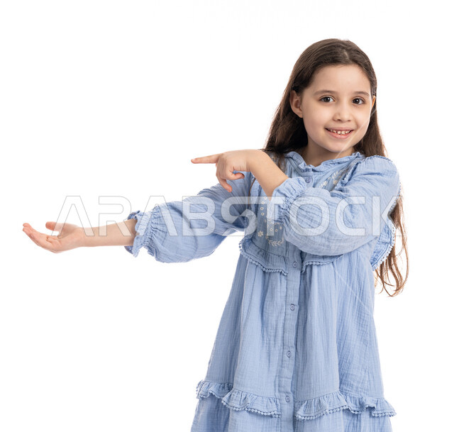 النقر بالأصبع على الشاشه, بنت سعودية ترتدي الفستان و تستخدم حاسة اللمس لتحريك العناصر الهولوجراميه, بورتريه مقرب لفتاة عربية اماراتية خليجية تشير الى شيء ما تحمله في يدها, الشعور بالإعجاب والرضا, خلفية بيضاء