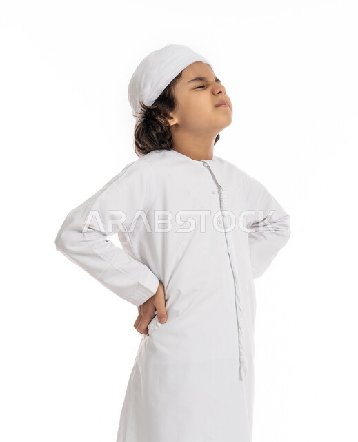 فتى سعودي يعاني من التعب والإرهاق و الحاجه للعلاج، وجع العظام والعضلات, بورتريه مقرب لولد عربي اماراتي سعودي يرتدي العمامة والكندورة, يضع يديه على ظهره بإيماءات تدل على الشعور بالألم, طلب المساعده للذهاب الى الطبيب, خلفية بيضاء