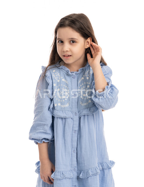 إيماءات الإنصات وكشف الاسرار, سماع الأحاديث و النقاشات، محاولة التجسس والتنصت, بورتريه مقرب لفتاة عربية اماراتية خليجية ترتدي الفستان تضع يديها خلف اذنيها, بنت سعودية تقوم بالإستماع و التركيز على الكلام, خلفية بيضاء