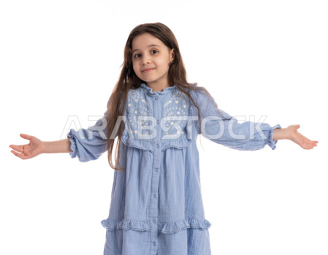 بنت سعودية تقف بتعابير الحيرة و التفكير، بورتريه مقرب لفتاة عربية خليجية امارتية ترتدي الفستان ترفع يديها بإيماءات الإنكار وعدم المعرفة، خلفية بيضاء