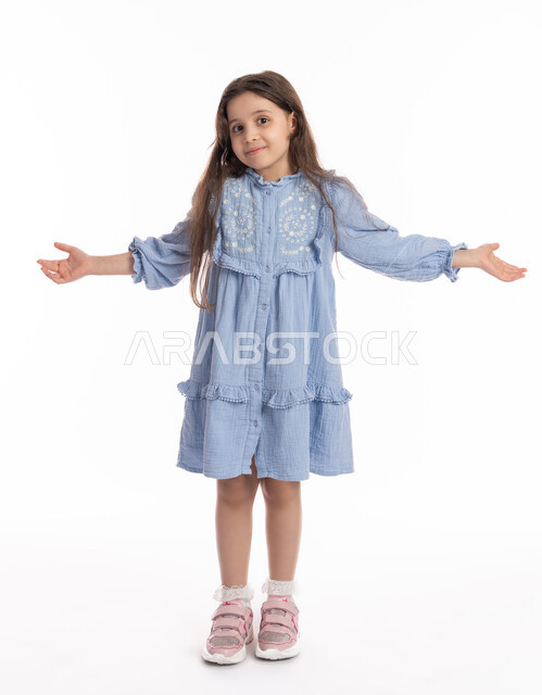 A Saudi girl standing with an expression of confusion and thought, portrait of an Arab Gulf Emirati girl wearing a dress, raising her hands with gestures of denial and lack of knowledge, full-length body portrait, white background