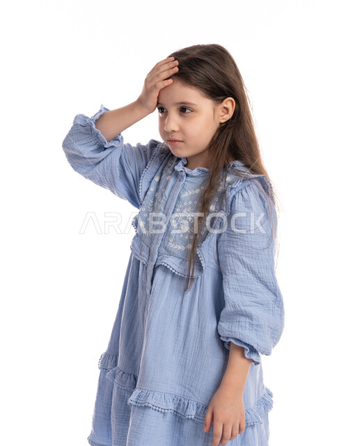 التفكير في شيء ما, طلب المساعده للذهاب الى الطبيب، بورتريه مقرب لفتاة عربيه اماراتية خليجيه تضع يديها على رأسها بايماءات الشعور بالصداع، الإحساس بالمرض و التعب والإرهاق, بنت سعودية ترتدي الفستان بحاجه للعلاج والدواء, خلفية بيضاء