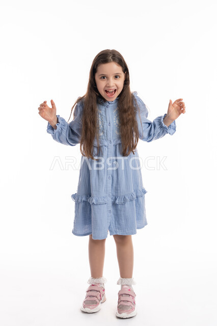 الصراخ والغضب من شيء ما, فتاة سعودية تقف بايماءات يدين ووجه تدل على الضجر و الاستياء وعدم الرضا, بورتريه لبنت عربية اماراتية خليجية ترتدي الفستان ترفع يديها للاعلى بتعابير العصبية, صورة الجسم بالكامل، خلفية بيضاء