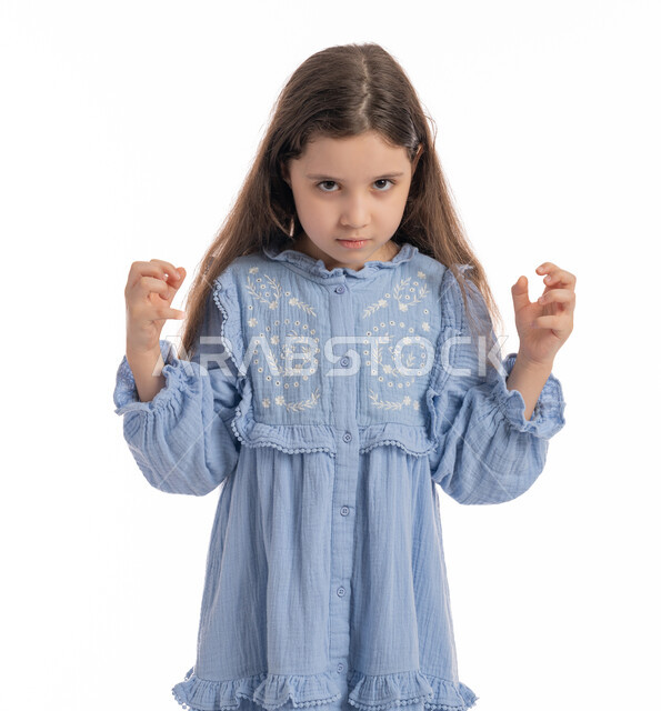 الغضب من شيء ما, فتاة سعودية تقف بايماءات يدين ووجه تدل على الضجر و الاستياء وعدم الرضا, بورتريه مقرب  لبنت عربية اماراتية خليجية ترتدي الفستان ترفع يديها للاعلى بتعابير العصبية, خلفية بيضاء