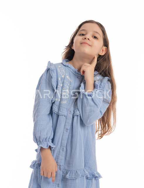 حركات وجه ويدين تدل على التفكير بشيء ما, بنت سعودية ترتدي الفستان تقوم بالتأمل والتفكير والتخطيط للمستقبل, مفهوم التمعن والتركيز، إيجاد حل لمشكلة ما, بورتريه مقرب لفتاة عربية اماراتية خليجية تضع يدها على وجهها، خلفية بيضاء