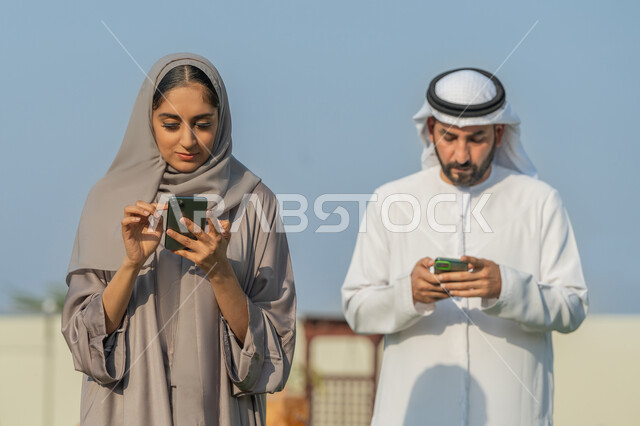 التواصل والدردشة مع الأصدقاء والأقارب عبر الجوال، استخدام الأجهزة التقنية والتكنولوجية الحديثة،  زوجان عربيان خليجيان اماراتيان يمسكان الهاتف المحمول، قضاء أوقات ممتعة في إحدى الشاليهات السياحية, التنزه في الهواء الطلق، متابعة أخبار مواقع السوشال ميديا