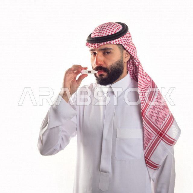 بورتريه لشاب سعودي خليجي يعاني من حمى شديدة ، ،ارتفاع درجات الحرارة ، جهاز قياس درجات الحرارة ، حالة مرضية ،  خلفية بيضاء