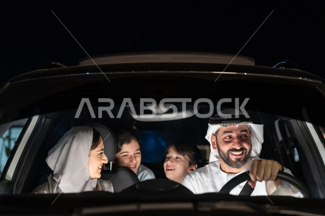 دردشه ومحادثات في الطريق، الإلتزام بربط حزام الأمان، رحله جماعيه في السياره, عائلة عربيه خليجية اماراتية سعيدة في رحلة بالسيارة يقومون بالتنزه في شوارع الامارات العربية المتحدة، قضاء وقت ممتع مع العائله، رجل عربي خليجي اماراتي يرتدي الكندورة والغترة البيضاء
