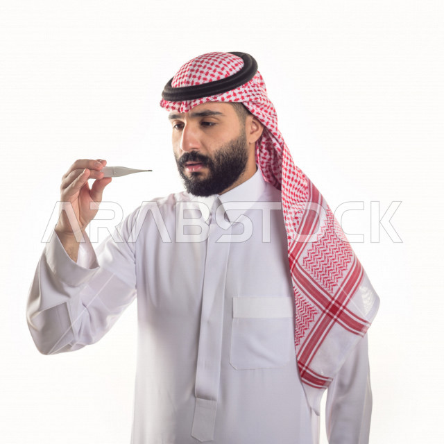 بورتريه لشاب سعودي خليجي يعاني من حمى شديدة ، ،ارتفاع درجات الحرارة ، جهاز قياس درجات الحرارة ، حالة مرضية ،  خلفية بيضاء