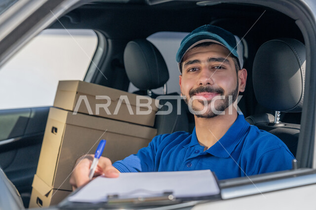 صورة مقربة لمندوب عربي خليجي إماراتي مبتسم يرتدي الزي الكاجوال و القبعة الزرقاء يجلس داخل السيارة وينظر إلى الكاميرا بتعابير البشاشة والرضا، اعطاء أوراق ومستندات استلام وتسليم الطرد, خدمات الشحن والتوصيل السريعة في الامارات